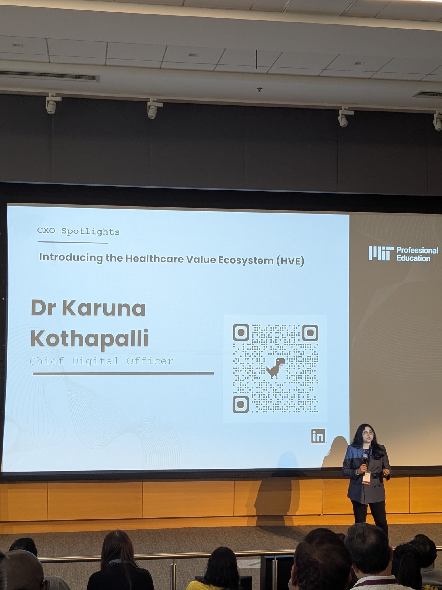 Dr. Karuna Kothapalli presenting on stage at MIT CXO Spotlight event